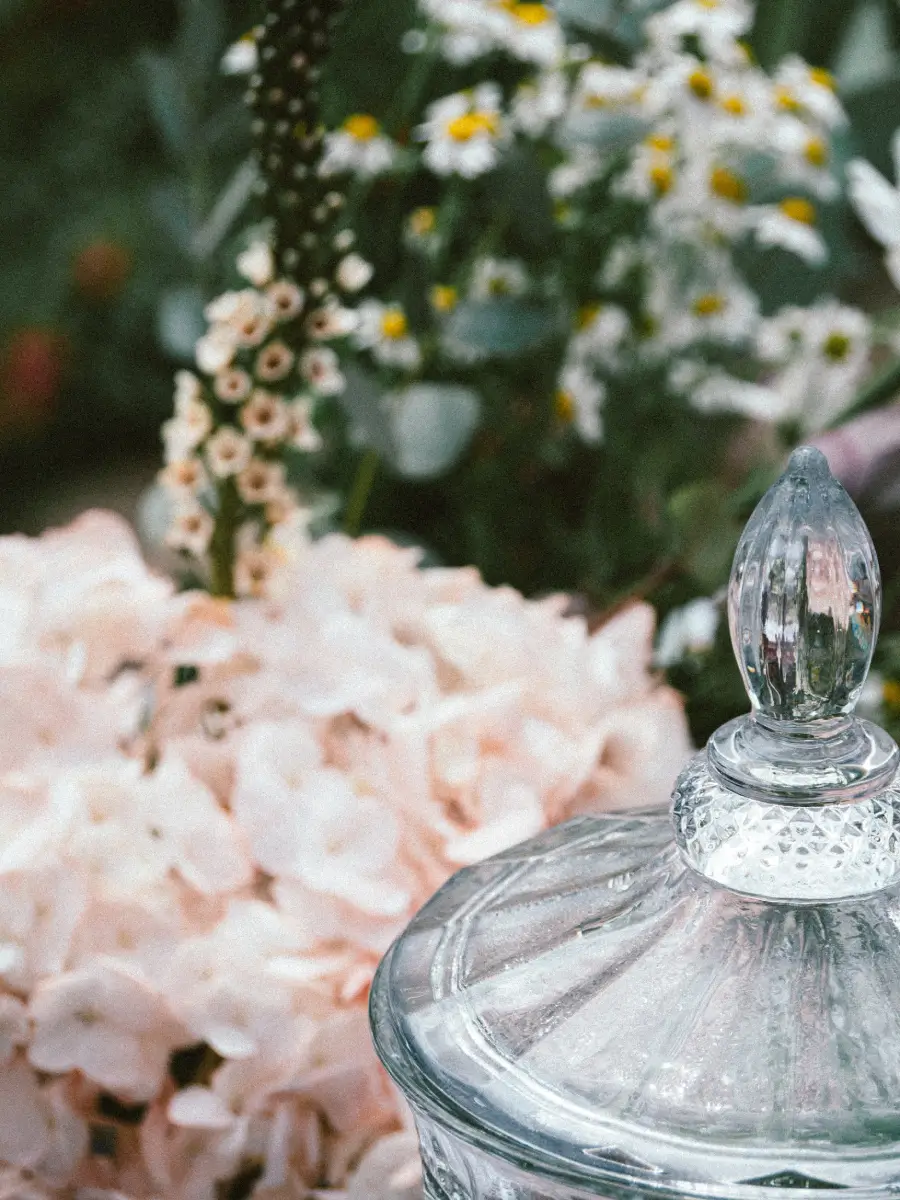 Jeu de fleurs en arrière-plan Vase vide au premier plan avec un bouquet flou de fleurs roses, blanches et jaune à l’arrière-plan.